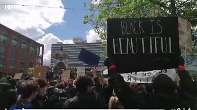 Protesters holding placards including "Black is Beautiful"