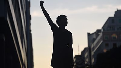 A file photo of a protester silhouette raises a fist during a protest against police brutality and the death of George Floyd.