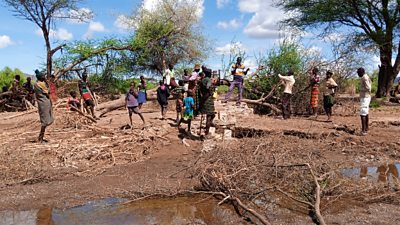 People in Kanukurudio village assemble around a water pump destroyed by flash flooding