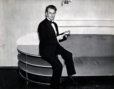 John Logie Baird seated on a Modern chair