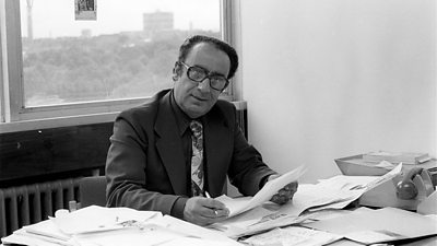 Mahendra Kaul sitting at a desk covered in papers