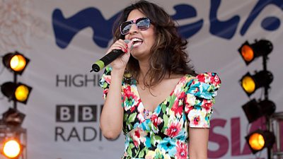 Noreen Khan holding a mic at an open air festival