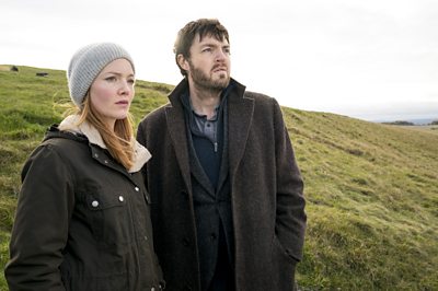 Robin Ellacott (HOLLIDAY GRAINGER), Cormoran Strike (TOM BURKE)(Image Credit: BBC/Bronte Films/Steffan Hill)