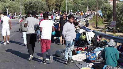 Migrants from Moria camp huddled on road