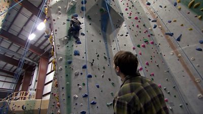 Matthew on the rock climbing wall as his friend Max watches