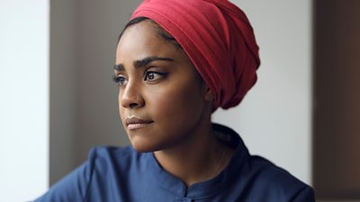 Nadiya Hussain  head and shoulder portrait looking left, wearing a red head covering and blue shirt