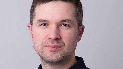 Charlie Swinbourne head shot looking straight to camera. Plain grey background. 