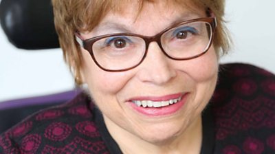 Judy Heumann smiling at camera. Close up shot. She's wearing glasses and has short red coloured hair.