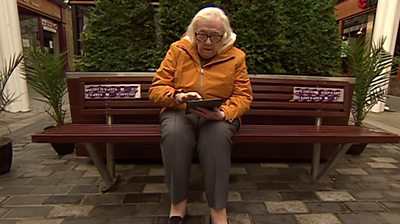 Margaret sitting on bench with tablet