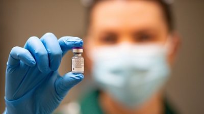 Nurse holds phial of vaccine