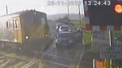 A freight train nearly hit a driver when he tried to beat crossing lights and his car became stuck.