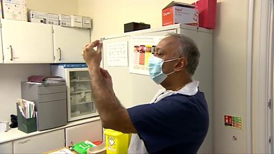 Dr Anil Mehta holds up a needle containing the Covid-19 vaccine.