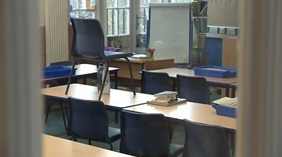 An empty classroom, desks stacked on tables
