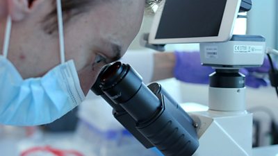A scientist at Bit.bio looks through a microscope