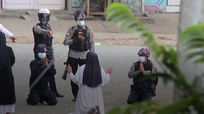 Nun kneeling in front of police