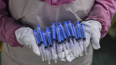 A worker displays syringes at the Hindustan Syringes factory in Faridabad