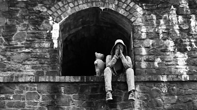 Man sitting on a ledge next to a bear