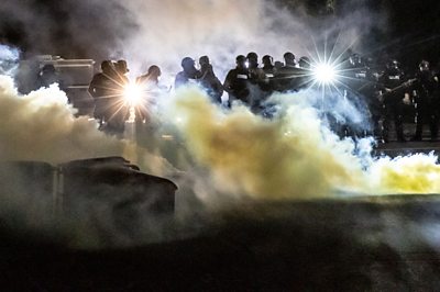 Police officers amid tear gas during protest