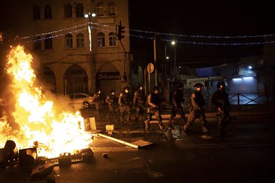 Police walking past a fire during clashes