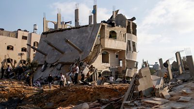 Palestinians gather around a building destroyed by an Israeli airstrike on 13 May 2021