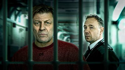 Two male characters, a prisoner and a man in prison guard's uniform behind bars looking solemn.