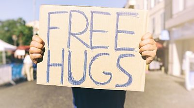 Person holds up free hugs sign