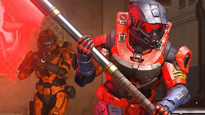 Two players wearing Spartan armour run with a flag in Halo multiplayer