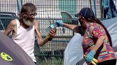 An outreach worker handing a water bottle to a homeless person