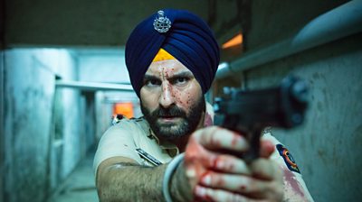 Sartaj Singh (Saif Ali Khan) face covered in blood in a subway holding his gun in front of him.