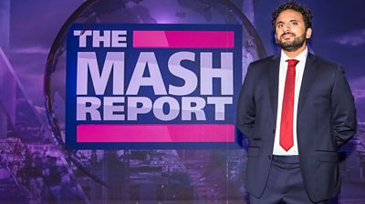 Nish Kumar standing next to the Mash Report branding. He's wearing a blue suit, white shirt and red tie. His arms are behind him as he looks seriously to the camera.