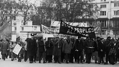 Black and white image with scores of people marching in London's Hyde Park in 1970s. Banners include text saying Black People's Alliance and another (partially obscured) says Pakistani Workers, Birmingham