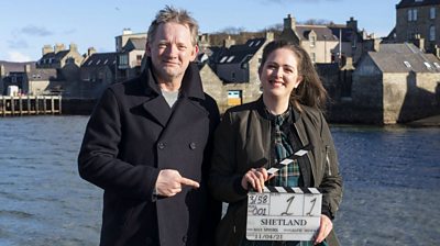 Behind the scenes with actors holding a clapperboard 