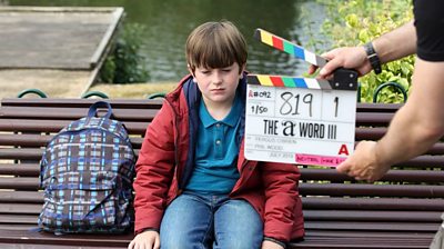 Behind the scenes with a young actor on a bench with a clapperboard