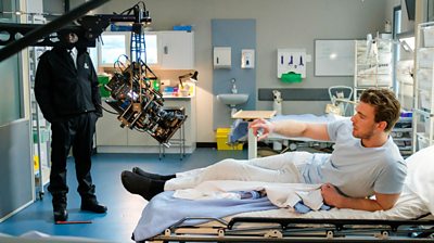 Behind the scenes with an actor on a bed with a large camera over him