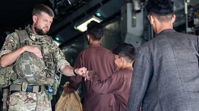 A member of the UK Armed Forces fist-bumping a child evacuee at Kabul airport