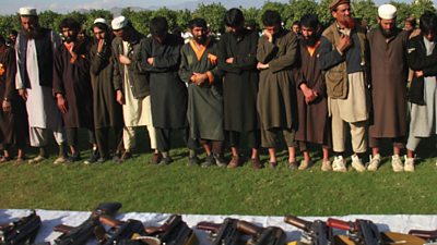 Group of fighters stand in front of weapons on the ground