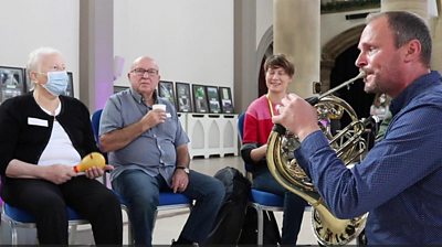 Man playing french horn in music class