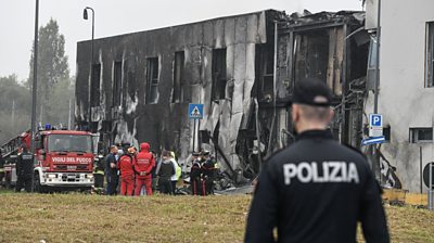 A policeman looking at the office building that a private jet crashed into in Milan