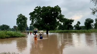 Women wade through floodwater