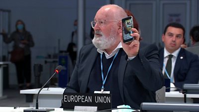 Frans Timmermans holding up phone