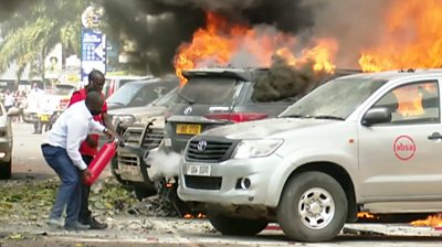 Two men using a fire extinguisher to put out a large fire