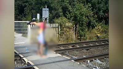 A teenage girl performing a handstand at a level crossing