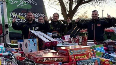 Four men next to Christmas presents