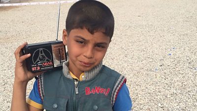 An Iraqi child from an IDP camp is shown listening to a radio distributed with support from UNHRC, BBC Media Action and Radio Nawa.
