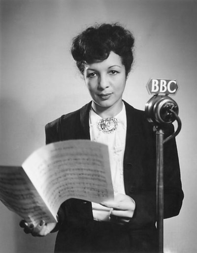 Evelyn Dove at the microphone with a musical score