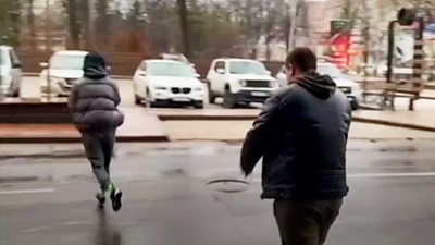 People run to their car in a street in Donetsk