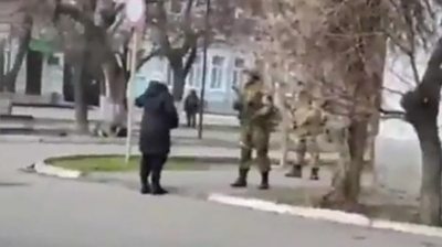 A Ukrainian woman confronts an armed Russian soldier