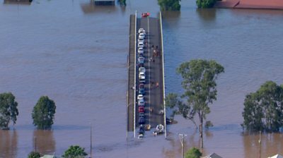 Cars trapped on bridge surrounded by floodwaters