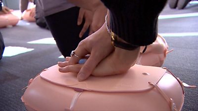 Hands pressing down on a CPR dummy