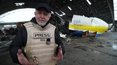 The BBC's Jeremy Bowen surrounded by airport wreckage